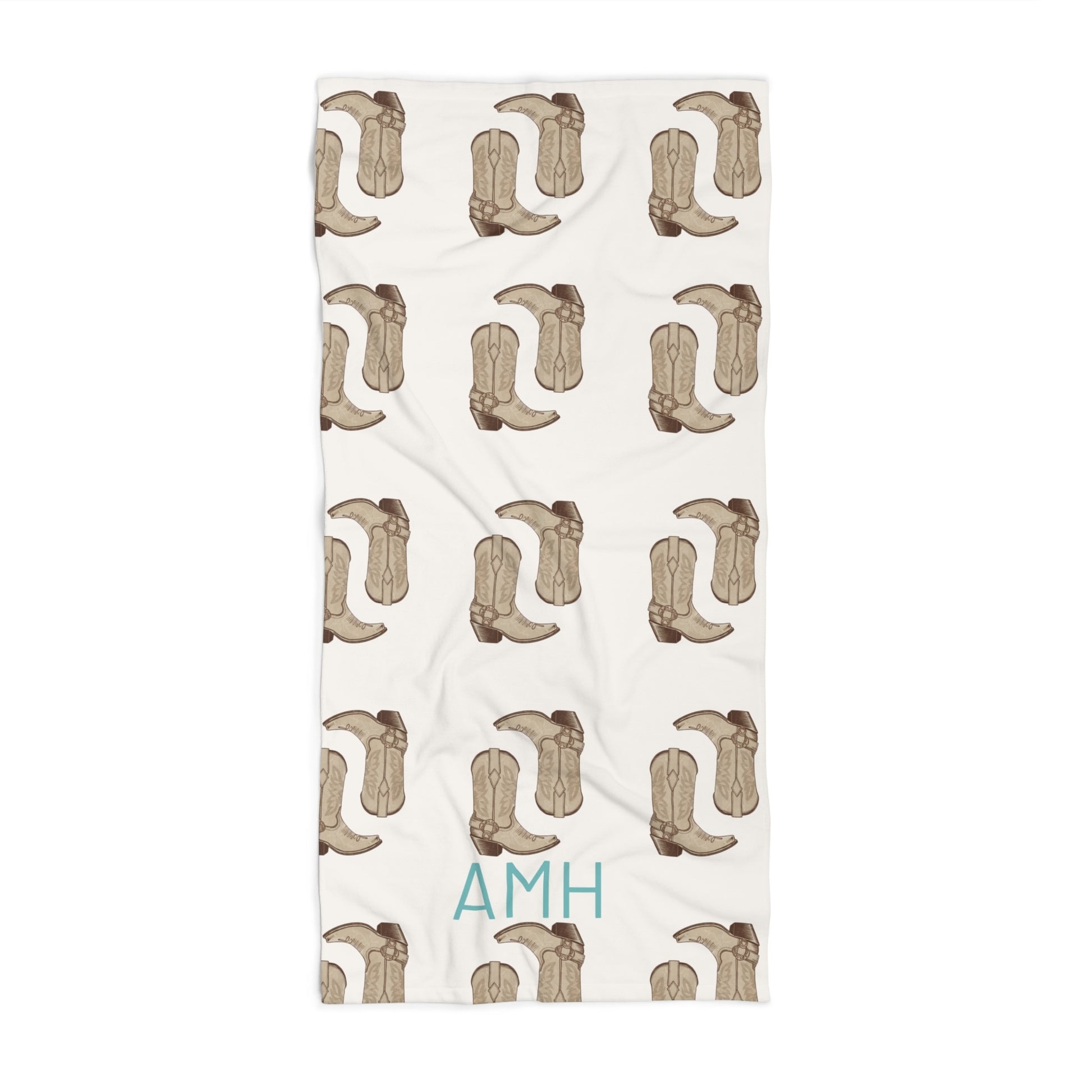 Beige towel with cowboy boot pattern and 'AMH' branding on a white background