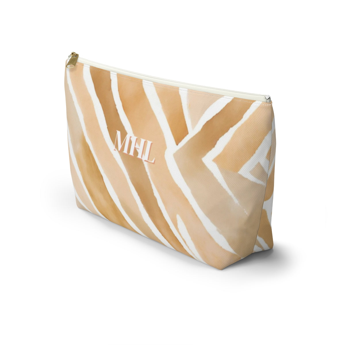 side view of monogrammed cosmetic travel bag in a light tan, apricot  and cream abstract pattern with white and gold zipper