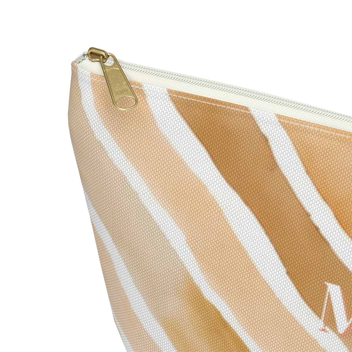 close up view of a monogrammed cosmetic travel bag in a light tan, apricot  and cream abstract pattern with white and gold zipper