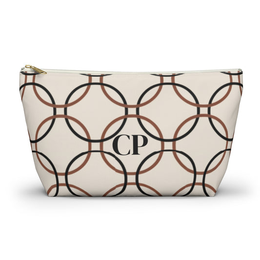 Monogrammed cosmetic travel bag with repeating pattern of black and brown interlocking circles on a cream background