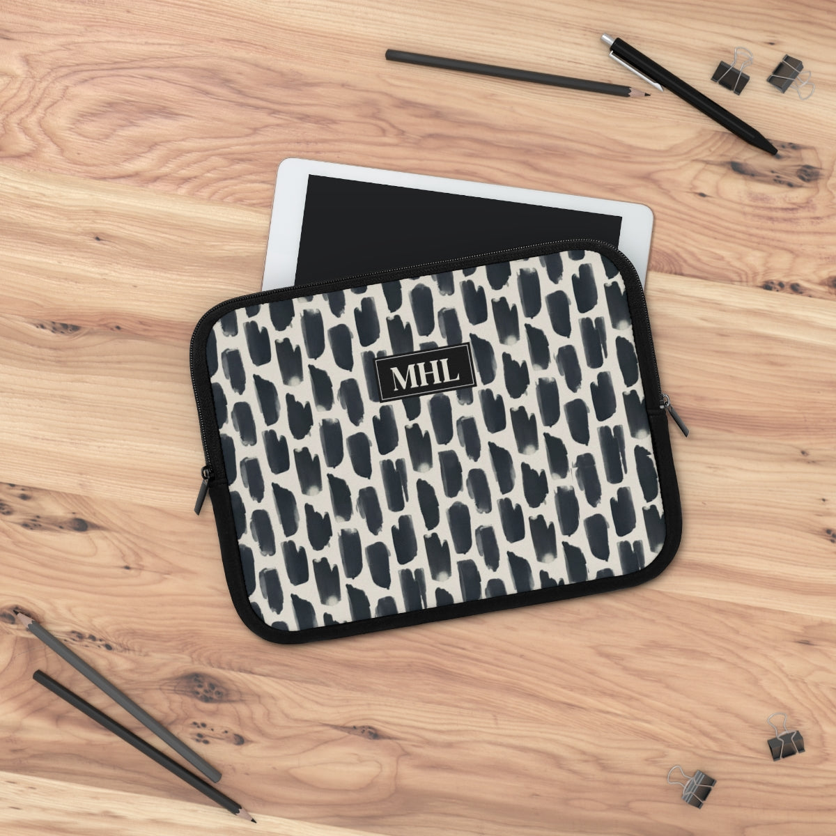 front view of personalized laptop sleeve with a cream colored monogram on  a repeating abstract pattern of animal spots in black