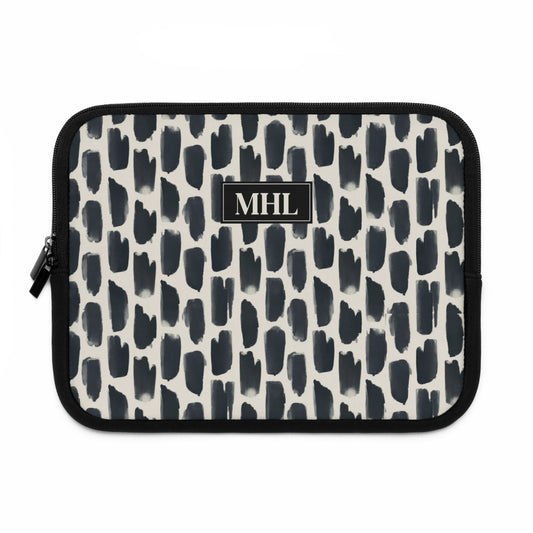 front view of personalized neoprene laptop sleeve with a cream colored monogram on  a repeating abstract pattern of animal spots in black