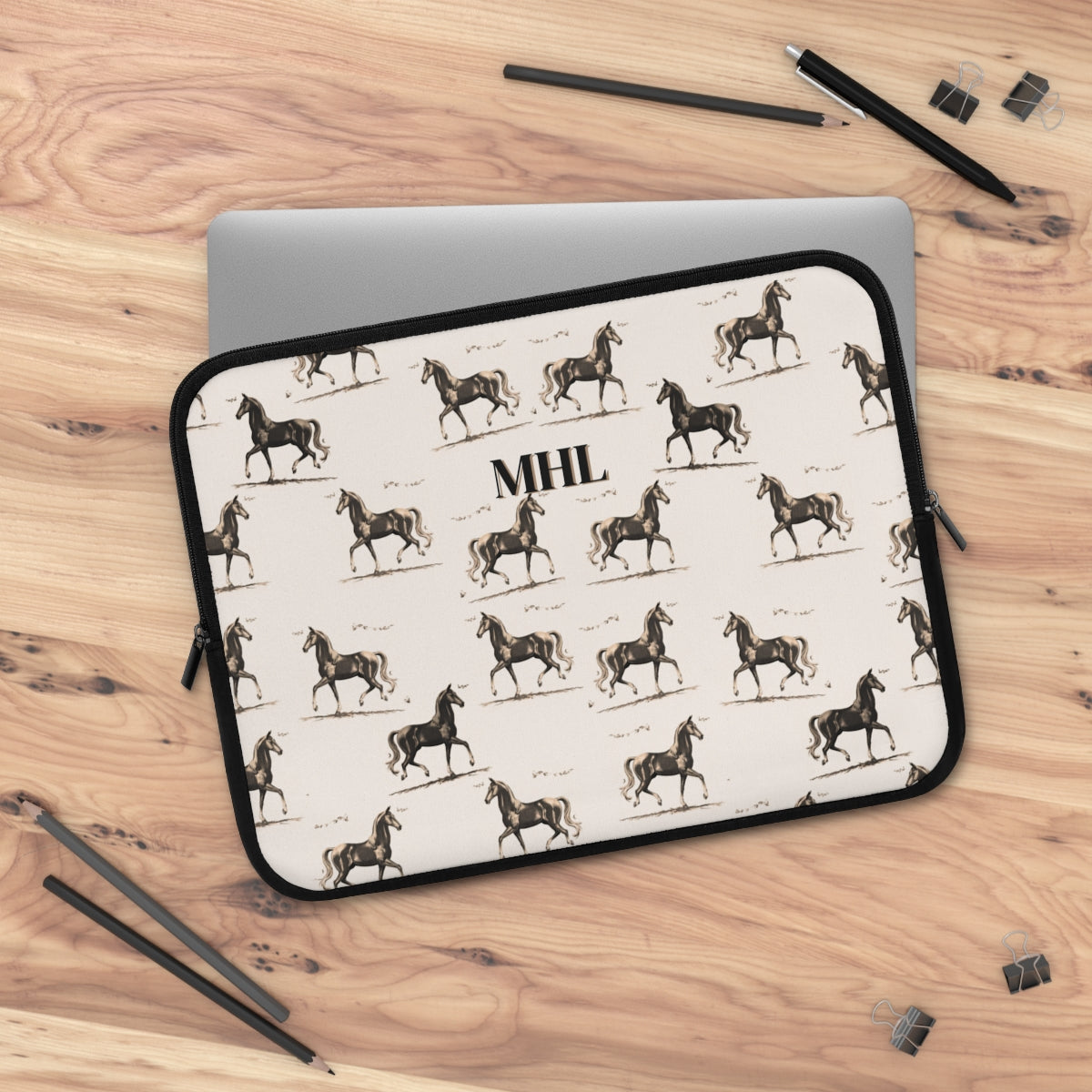 Monogrammed neoprene laptop case with a repeating pattern of horses on a cream background 