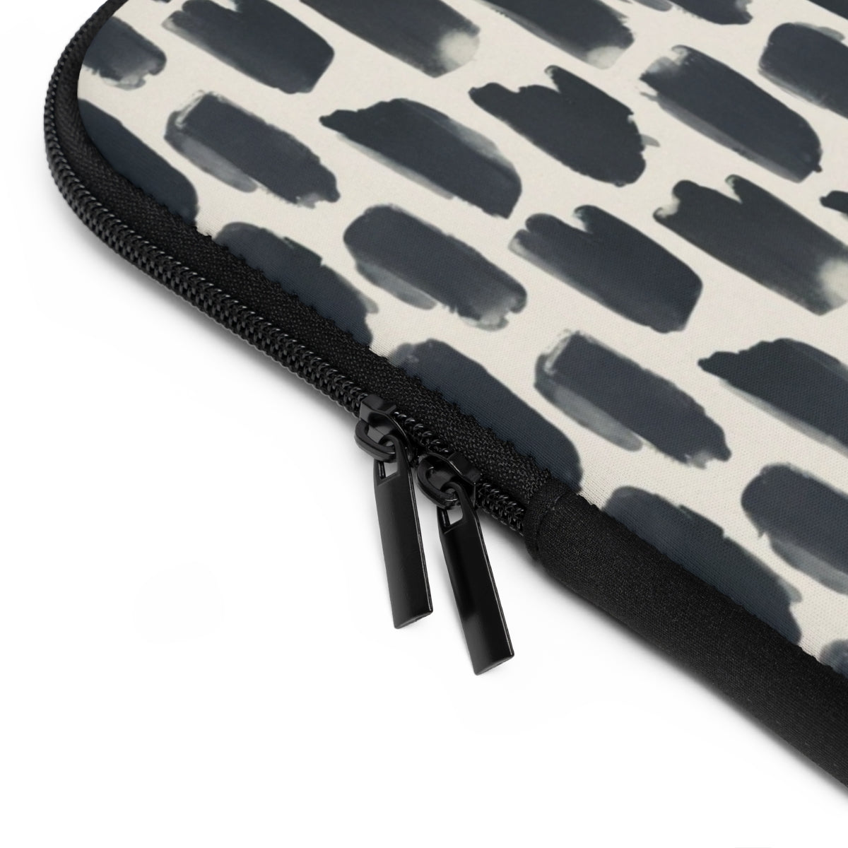 close up view of zipper of front view of personalized laptop sleeve with a cream colored monogram on  a repeating abstract pattern of animal spots in black