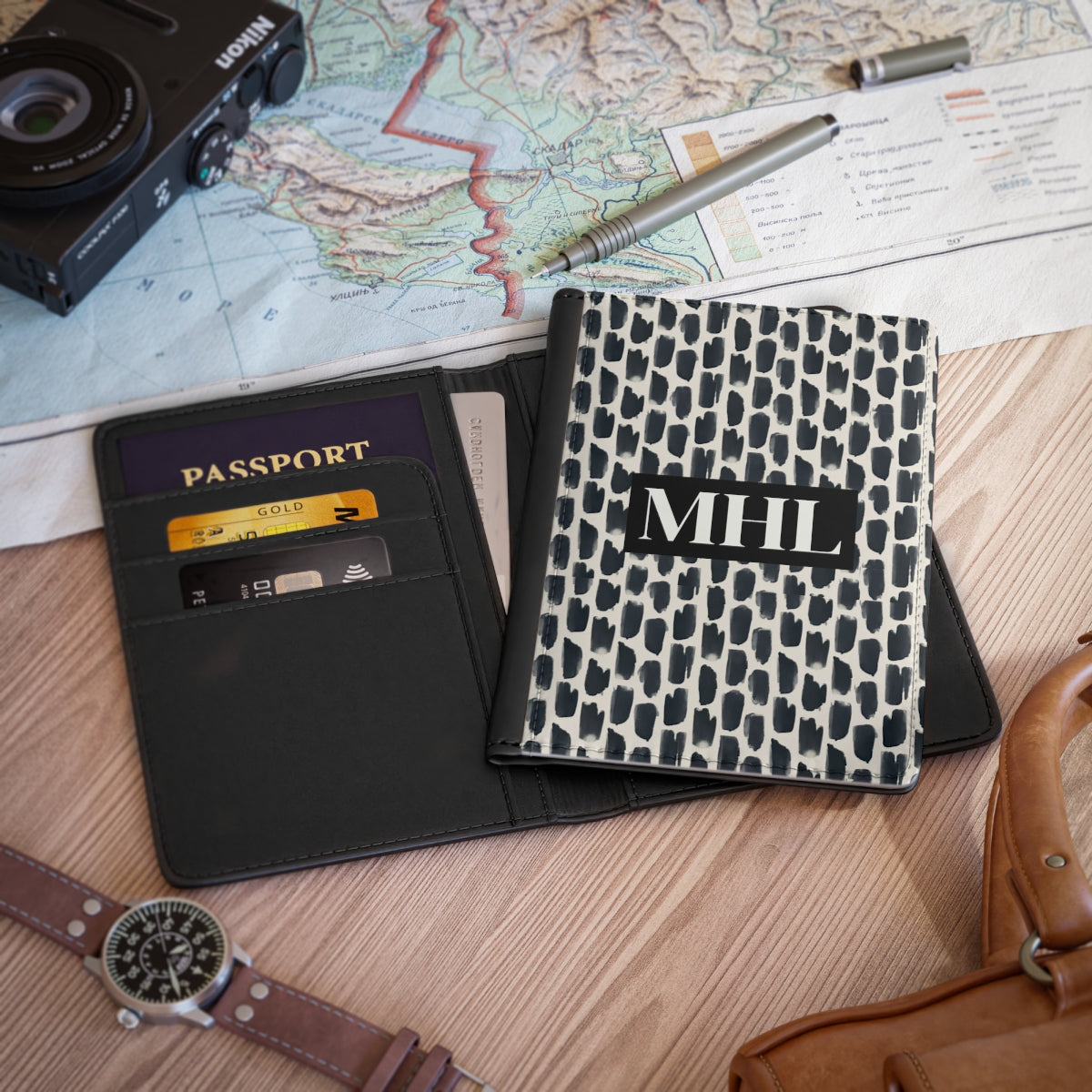 Front of personalized passport cover with a cream colored monogram on  a repeating abstract pattern of animal spots in black