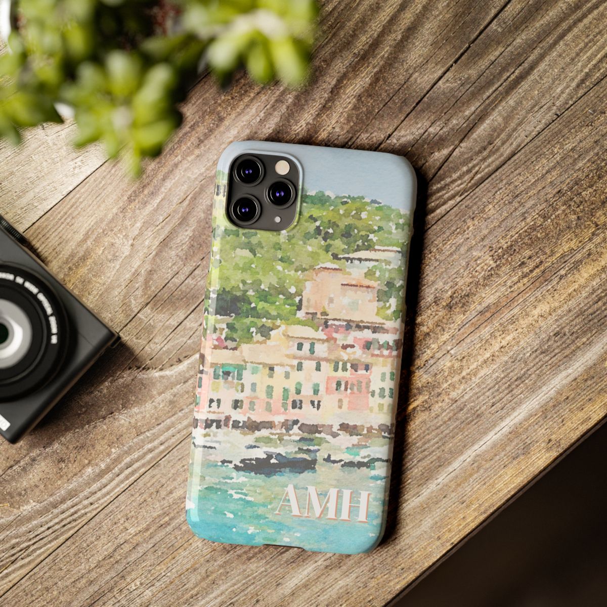 front view of personalized slim iPhone case with cream monogram on a background image of Portofino in a watercolor style.